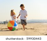 Beautiful brother and sister play with a beach ball outdoors