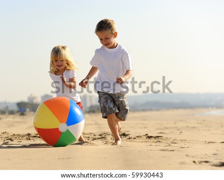 Beautiful brother and sister play with a beach ball outdoors