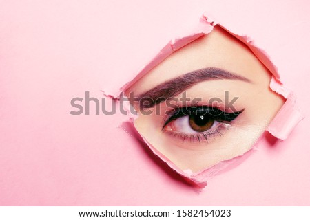 Beautiful brown eye, perfect eyebrows. Beauty salon, eyebrow master, tattoo master shooter and eyebrow. Beautiful eye on a pink background.