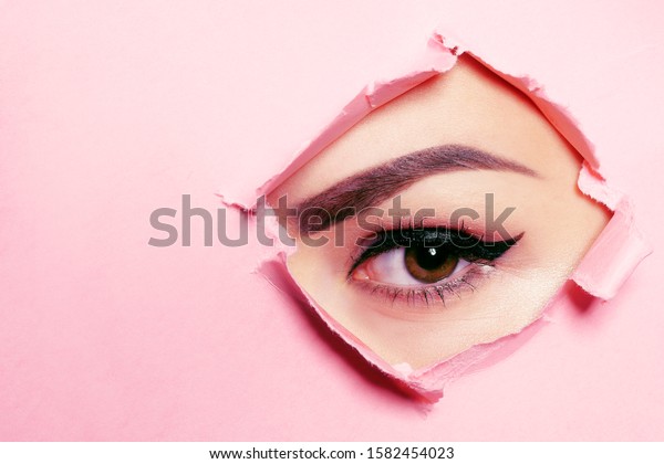 Beautiful brown eye, perfect eyebrows. Beauty\
salon, eyebrow master, tattoo master shooter and eyebrow. Beautiful\
eye on a pink\
background.