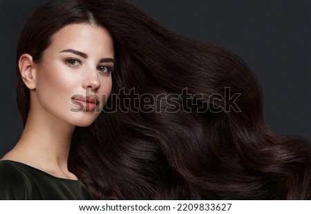 Beautiful brown-haired girl with a perfectly curls hair, and classic make-up. Beauty face and hair. Picture taken in the studio.