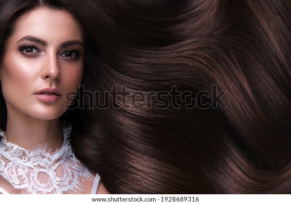 Beautiful brown-haired girl with a perfectly\
curls hair, and classic make-up. Beauty face and hair. Picture\
taken in the studio.