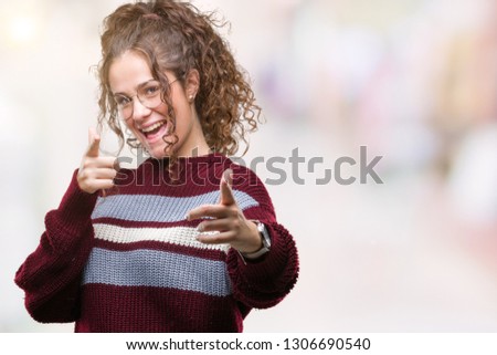 Beautiful brunette curly hair young girl wearing glasses over isolated background pointing fingers to camera with happy and funny face. Good energy and vibes.