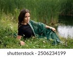 Beautiful  brunette extra long braided hair girl in Indian traditional dress posing near river . Portrait of young attractive stylish woman in sari on  green nature background.