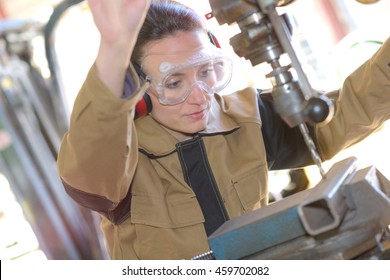 beautiful brunette factory worker drilling a piece - Powered by Shutterstock