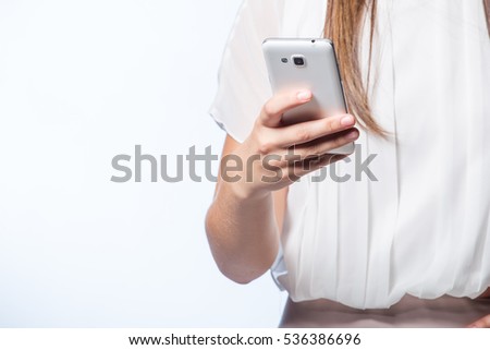 Beautiful brunette female business / professional model talking, texting, taking a selfie on her smart phone in a studio on white background