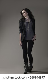 Beautiful Brunette Girl In Black Leggings, Grey Shirt And Black Blazer With Edgy, Dark Makeup And Hair.