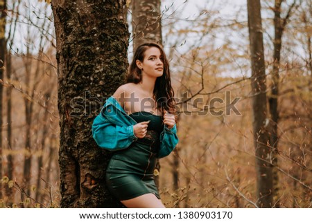 Beautiful brunette girl dressed with black dress and jeans jacket. Photo session in forest with beautiful caucasian teenager girl 