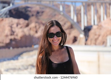 Beautiful Brunette Girl Model In Glasses Smiling Against The Background Of The Hoover Dam. Arizona Nevada USA. Close Up. 