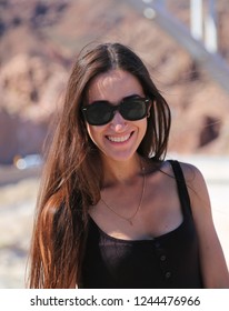 Beautiful Brunette Girl Model In Glasses Smiling Against The Background Of The Hoover Dam. Arizona Nevada USA. Close Up. 