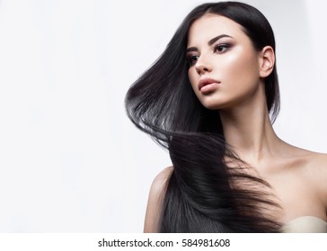 Beautiful brunette girl in move with a perfectly smooth hair, and classic make-up. Beauty face. Picture taken in the studio on a white background.