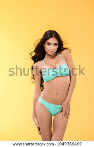 beautiful brunette girl posing in bikini, isolated on yellow
