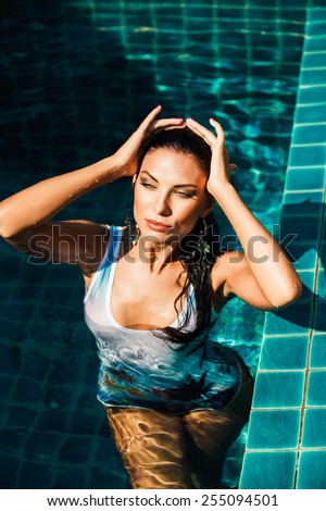 beautiful brunette girl posing in blue bikini in the pool