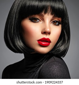 Beautiful brunette girl with red lips and black bob hairstyle. Pretty young woman with black hair. Closeup portrait of a model with bright makeup on a face. Fashion portrait of a pretty lady.