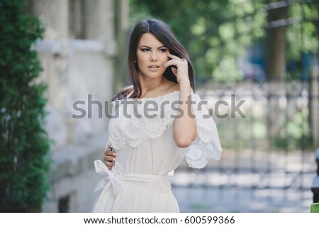 beautiful brunette girl standing in a summer city