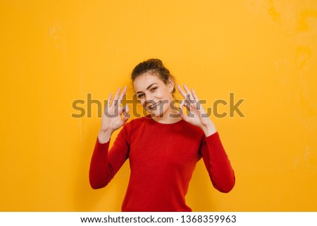 A beautiful brunette girl who shows gestures and is happy on a yellow background
