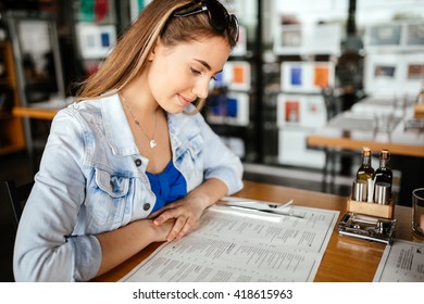 Beautiful Brunette Glancing Through Menu Deciding On What To Order