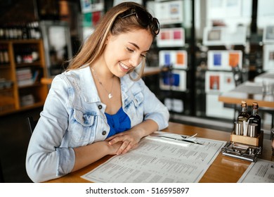 Beautiful Brunette Glancing Through Menu Deciding On What To Order