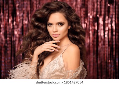 Beautiful brunette with Healthy wavy hair. Glamour eye Makeup. Fashion Beauty Girl with manicured nails. Isolated on bright bokeh Christmas lights Background.