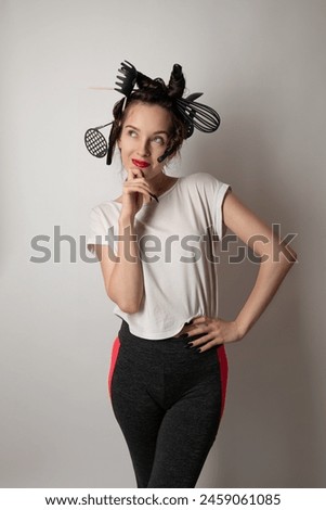 beautiful brunette housewife girl with kitchen utensils in her hair instead of curlers on a white background