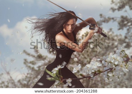 Beautiful Brunette with katana sword in spring floral environment
