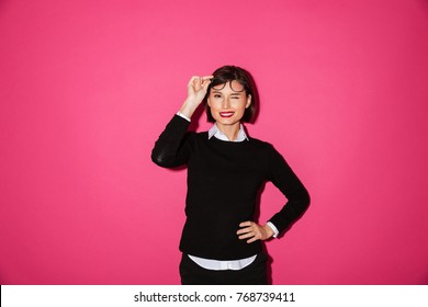 Beautiful Brunette Lady In Businesswear Taking Off Her Glasses And Winking Isolated Over Pink