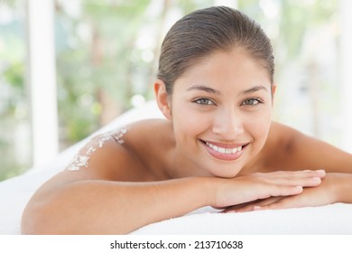 Beautiful brunette lying on massage table with salt scrub on back at the health spa