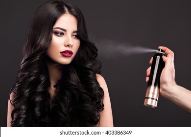 Beautiful Brunette Model: Curls, Classic Makeup And Red Lips With A Bottle Of Hair Products. The Beauty Face. 