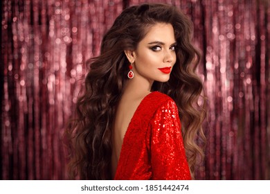 Beautiful brunette in red dress with Healthy wavy hair. Glamour Makeup. Fashion Beauty Girl Isolated on bright bokeh party Christmas Background. 