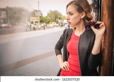 Beautiful Brunette Sexy Spy Agent (killer Or Police) Woman In Leather Jacket And Red Luxury Dress With A Binocular In Her Hand Stalking Someone, To Catch Him In European City.