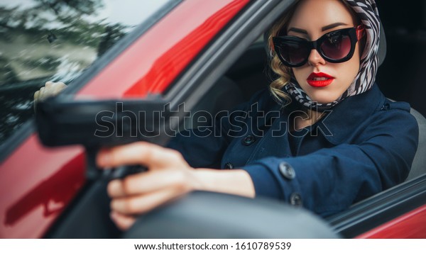 Beautiful brunette sexy spy agent (killer or\
police) woman in leather jacket and jeans with a gun in her hand\
driving a car after someone, to catch\
him.