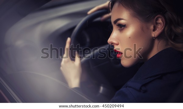 Beautiful brunette sexy\
spy agent (killer or police) woman in jacket driving a car after\
someone, to catch him