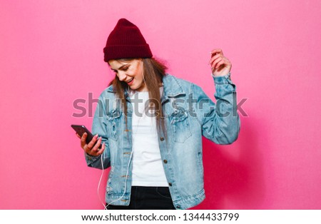A beautiful brunette singing girl listening to music in her headphones and dancing in the red background