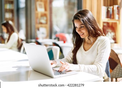 Beautiful brunette using notebook in cafe - Shutterstock ID 422281279