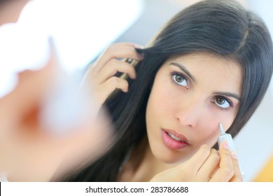 Beautiful brunette woman applying concealer