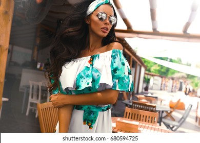 Beautiful brunette woman between palm leaves. Beauty summer make up photo.Close-up selfie-portrait attractive brunette girl with long hair,wear dress with palm print,sunglasses,Advertise your products