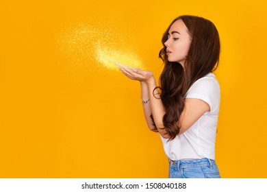 Beautiful Brunette Woman Blowing Glitter On Yellow Background