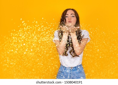 Beautiful Brunette Woman Blowing Glitter On Yellow Background