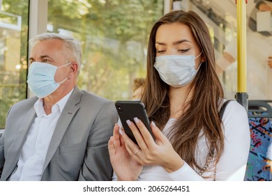 Beautiful Brunette Woman Holds Phone In Hand Browsing Social Media Student On Way Back From University By Bus On Face Is Protective Mask Required For Public Transportation Elderly Man Sit Next To Girl