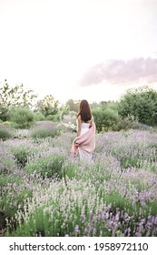 Beautiful brunette woman in lavender field on sunset. back view. Spring mood. Art noise
