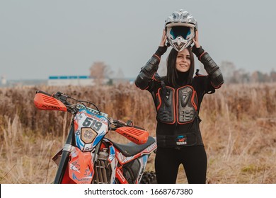 Beautiful Brunette Woman In Motorcycle Outfit. Female Motocross Racer Next To Her Motorcycle. Russia Moscow 20 October 2019