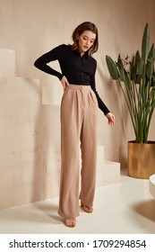 Beautiful Brunette Woman Natural Make Up Wear Fashion Clothes Casual Dress Code Office Style Black Blouse And Beige Pants Suit For Romantic Date Business Meeting Accessory Interior Stairs Flowerpot.