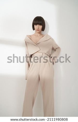 Beautiful brunette woman with natural makeup wear fashion pantsuit. 
Strict graphic bob haircut.  