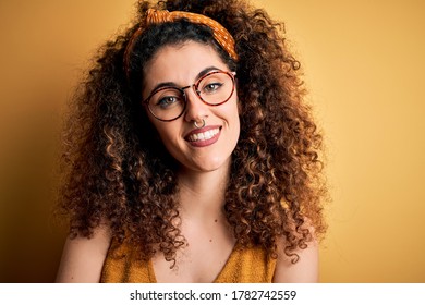 Beautiful brunette woman on vacation with curly hair and piercing wearing glasses and diadem happy face smiling with crossed arms looking at the camera. Positive person. - Powered by Shutterstock