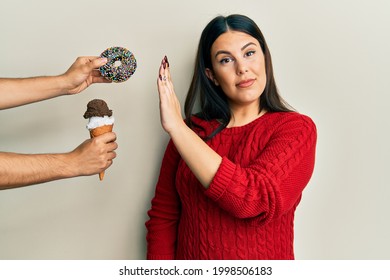 Beautiful brunette woman saying no to sweets on a healthy diet relaxed with serious expression on face. simple and natural looking at the camera.  - Shutterstock ID 1998506183