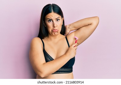 Beautiful Brunette Woman Shaving Armpit Hair With Razor Depressed And Worry For Distress, Crying Angry And Afraid. Sad Expression. 