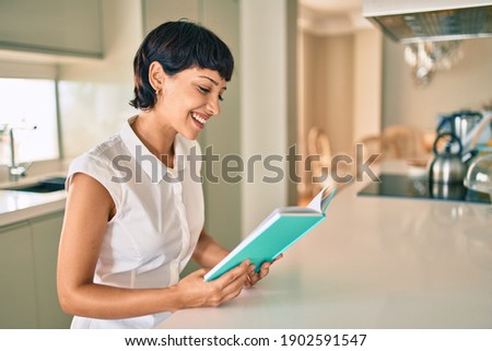 Beautiful brunette woman with short hair at home reading a book