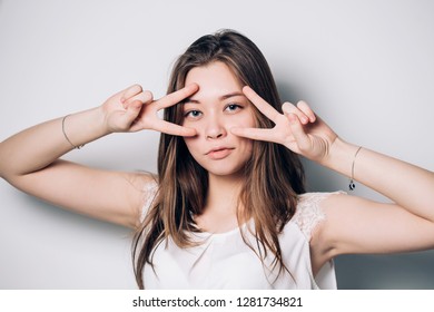 Beautiful brunette woman showing dancing gesture or victory sign on white background. Eyes, look, vision concepts