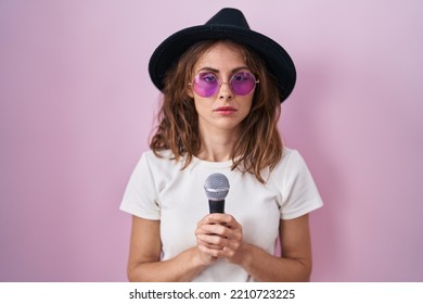 Beautiful Brunette Woman Singing Song Using Microphone Relaxed With Serious Expression On Face. Simple And Natural Looking At The Camera. 