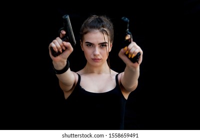 Beautiful brunette woman soldier takes aim with a gun isolated on black background. 
Self defense concept for women